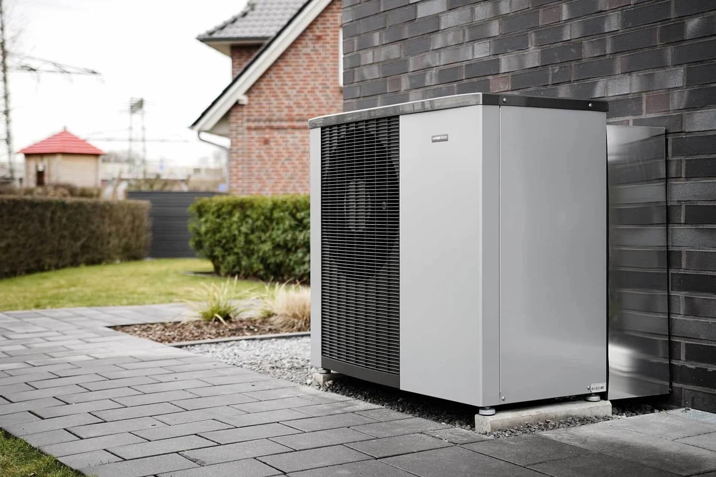 Buitenunit van een monoblock warmtepomp geïnstalleerd naast een huis, die duurzame verwarming biedt.